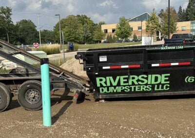 15 yard roll-off dumpster being delivered to job site, sliding off trailer into position