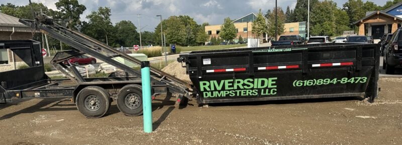 15 yard roll-off dumpster being delivered to job site, sliding off trailer into position