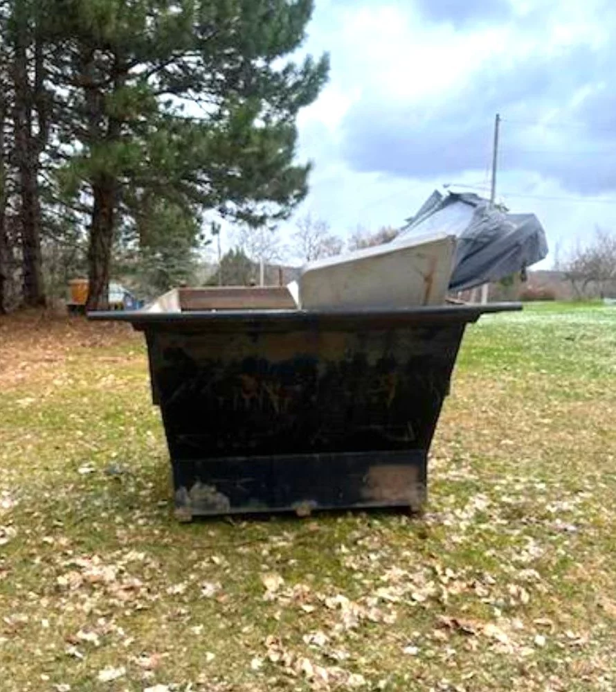 4 yard roll-off dumpster in yard, filled with waste