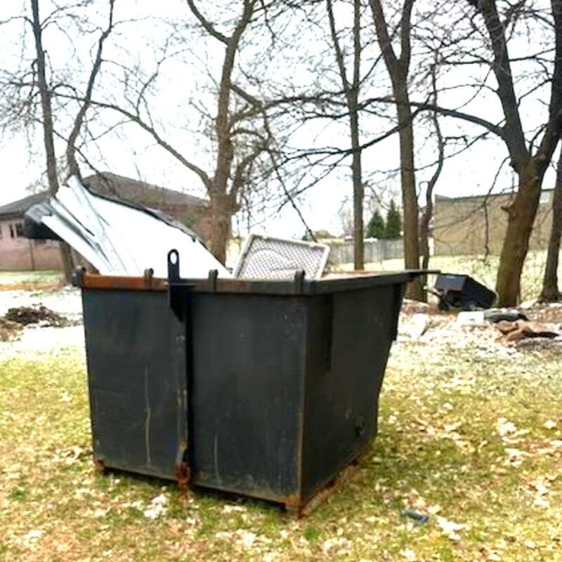 4 yard roll-off dumpster in yard full of discarded junk